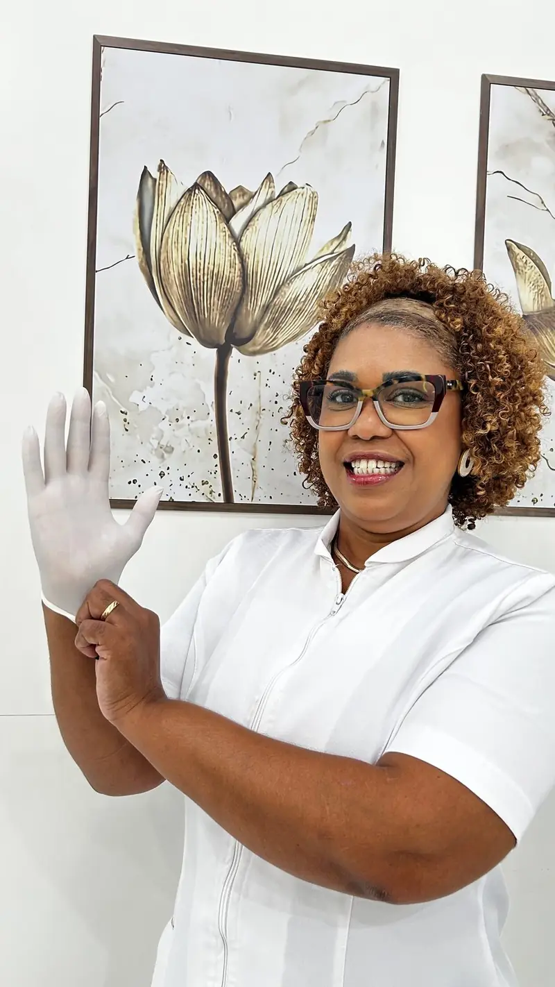 Adriana em atendimento, com uniforme e luvas