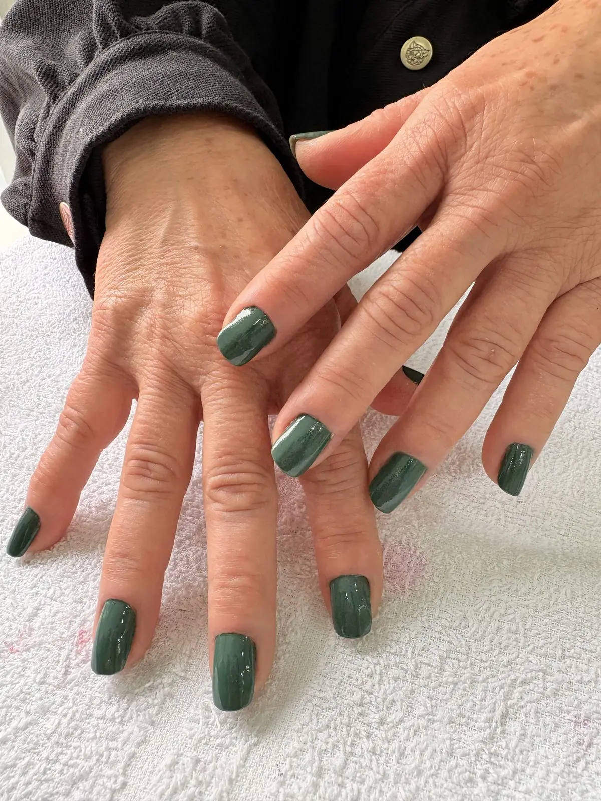 Mãos com esmalte verde escuro após manicure