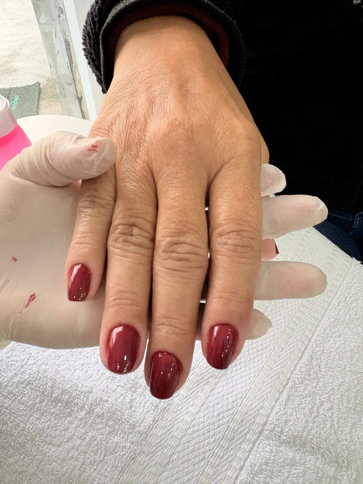 Mãos com esmalte vermelho escuro, durante o atendimento