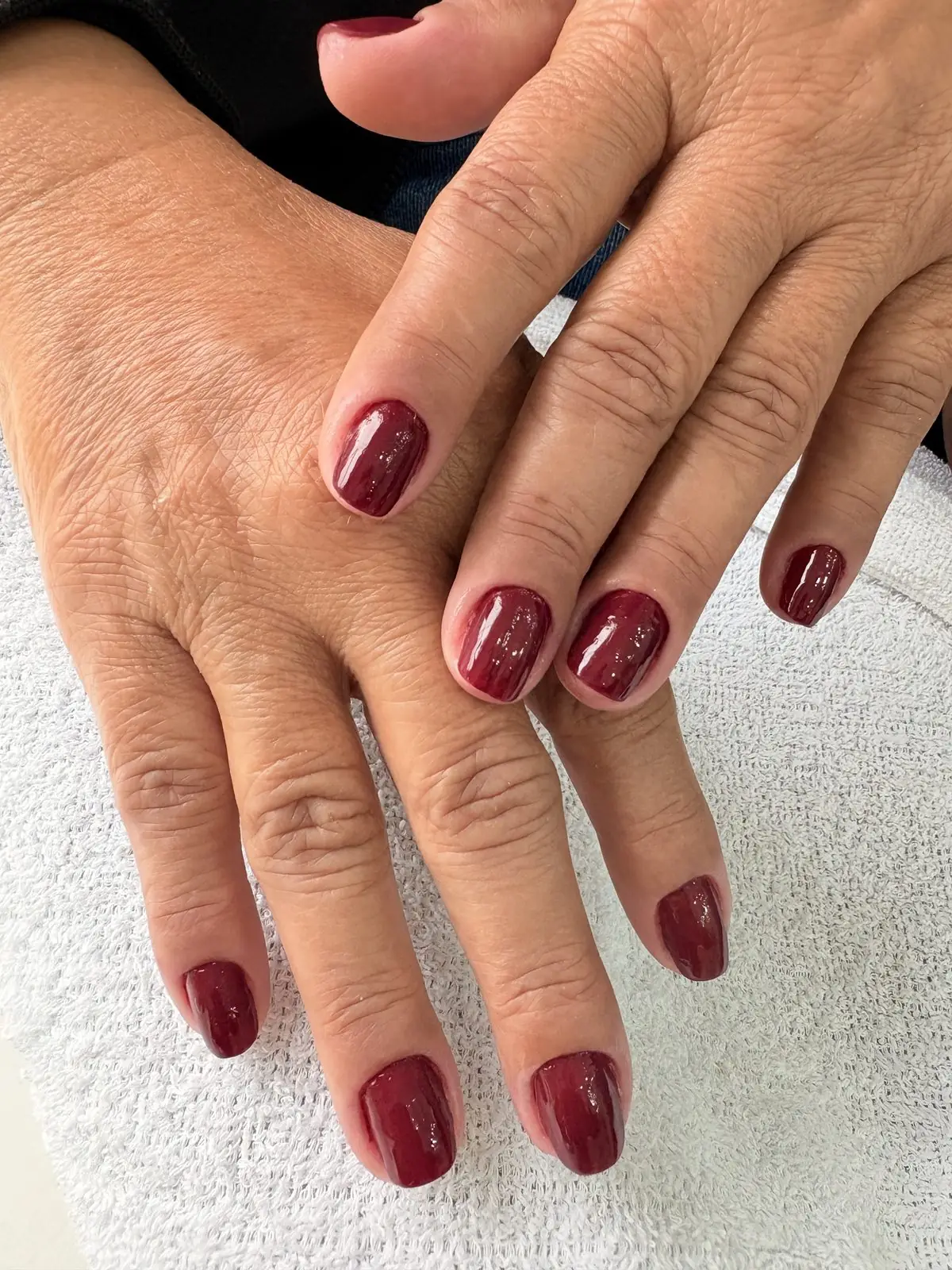 Mãos com esmalte bordô após manicure