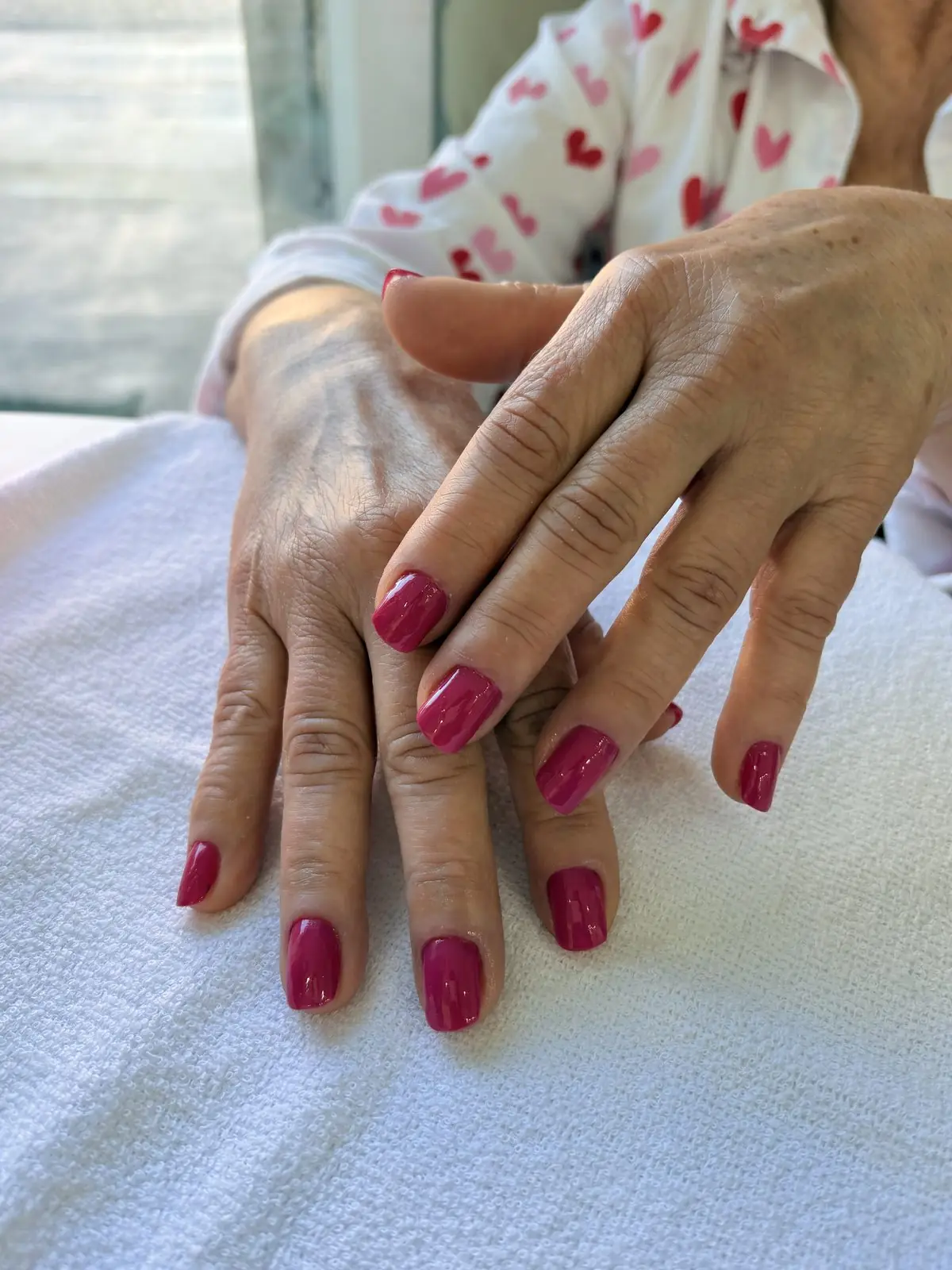 Mãos com esmalte magenta após manicure